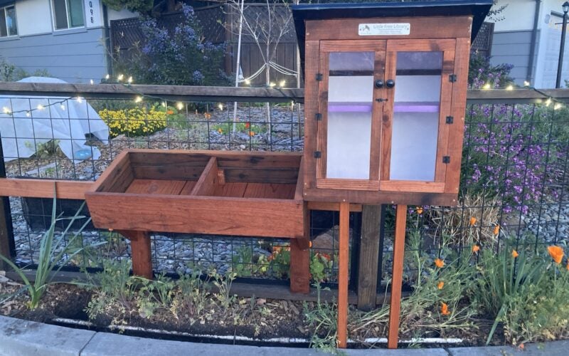 A wodden little free library in the house's front yard